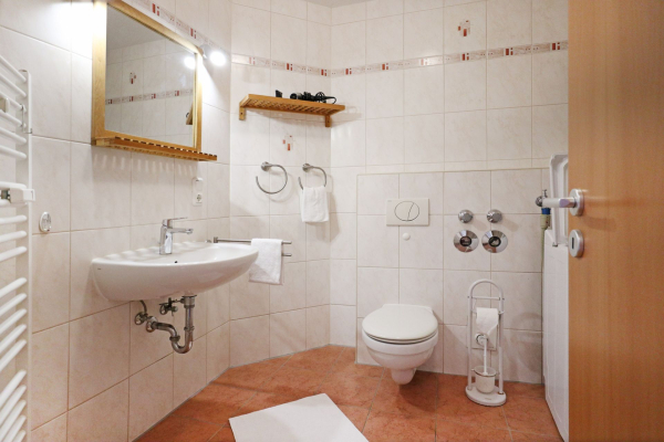 Blick in das Duschbad mit Waschmaschine, Waschbecken und Spiegel