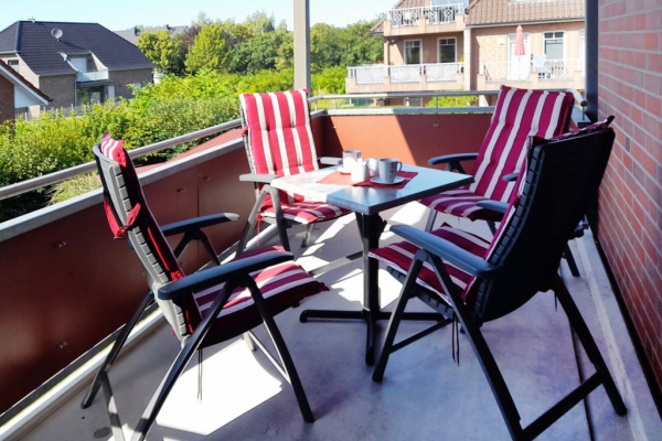 Blick auf den großen Balkon, mit einem Tisch und 4 Stühlen.