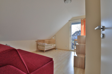 Strandgut Ferienhaus - Blick in das Gästezimmer mit Babybett und Wickeltisch