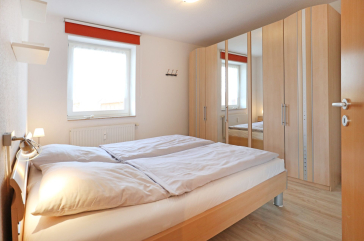 Blick in das Schlafzimmer mit einem Doppelbett und einem großen Kleiderschrank