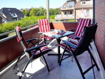 Blick auf den großen Balkon, mit einem Tisch und 4 Stühlen.