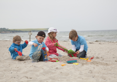 4 Kinder buddeln im Strandsand.
